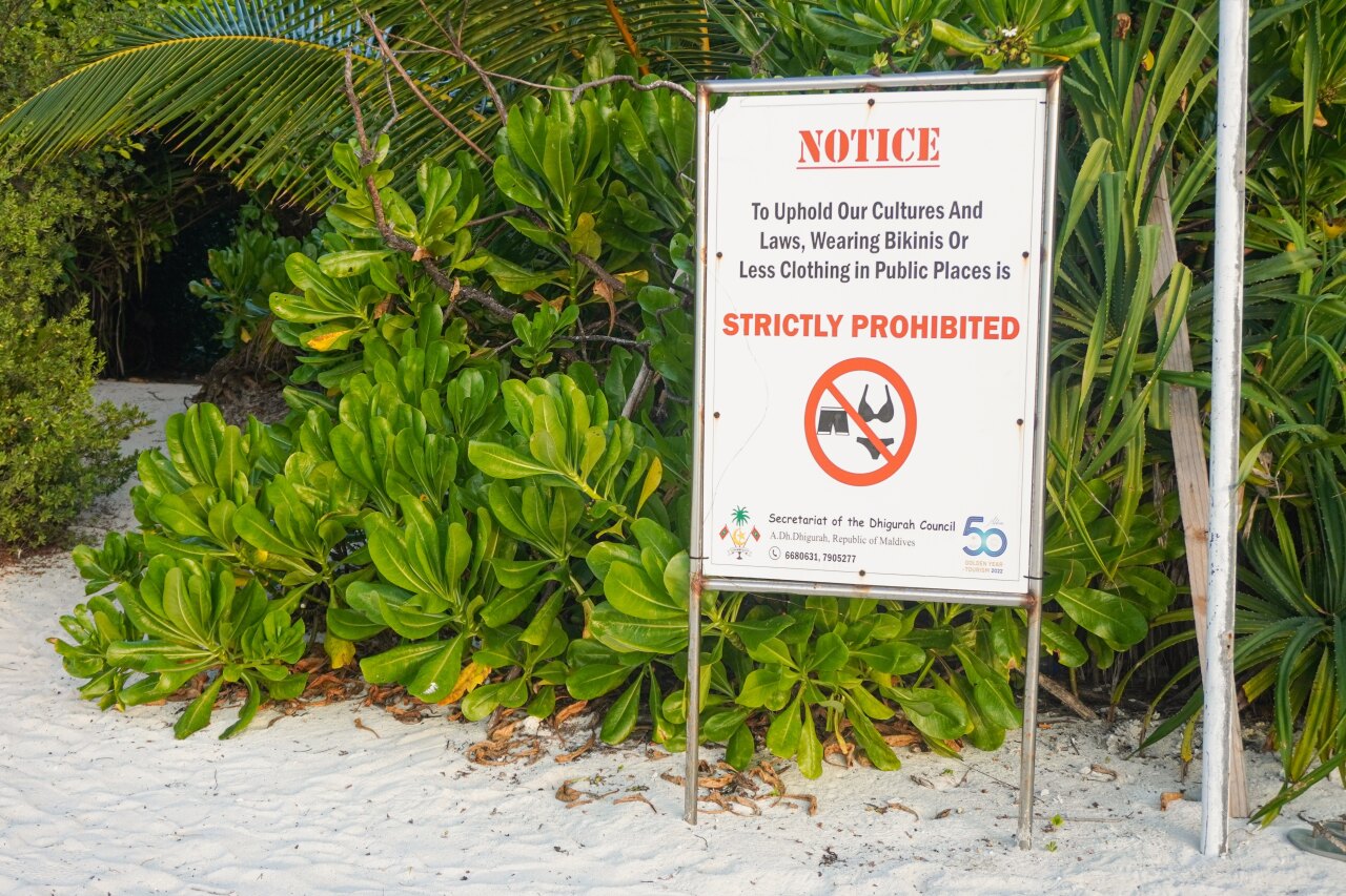 Un cartello su una spiaggia di un'isola locale alle Maldive che vieta rigorosamente di indossare bikini in pubblico.