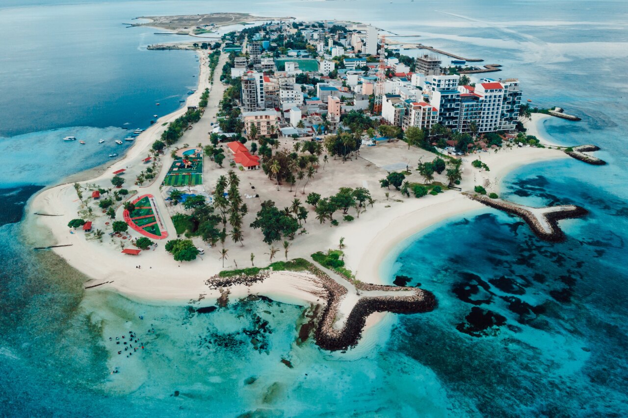 Drone perspective showing the local island of Maafushi in Kaafu Atoll with hotels, sandy beaches and turquoise water