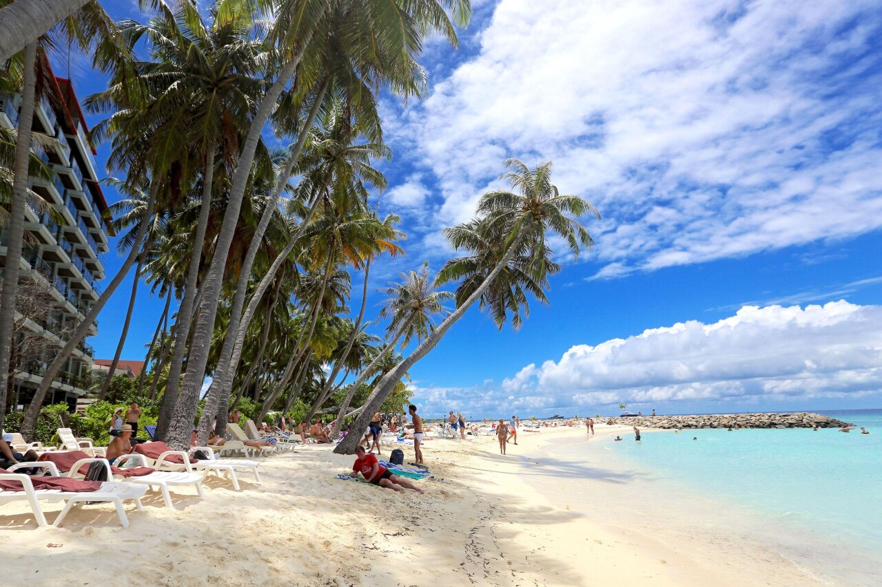 Tourists relaxing under palm trees on the sunny Bikini Beach at Maafushi Island in the South Male Kaafu Atoll.