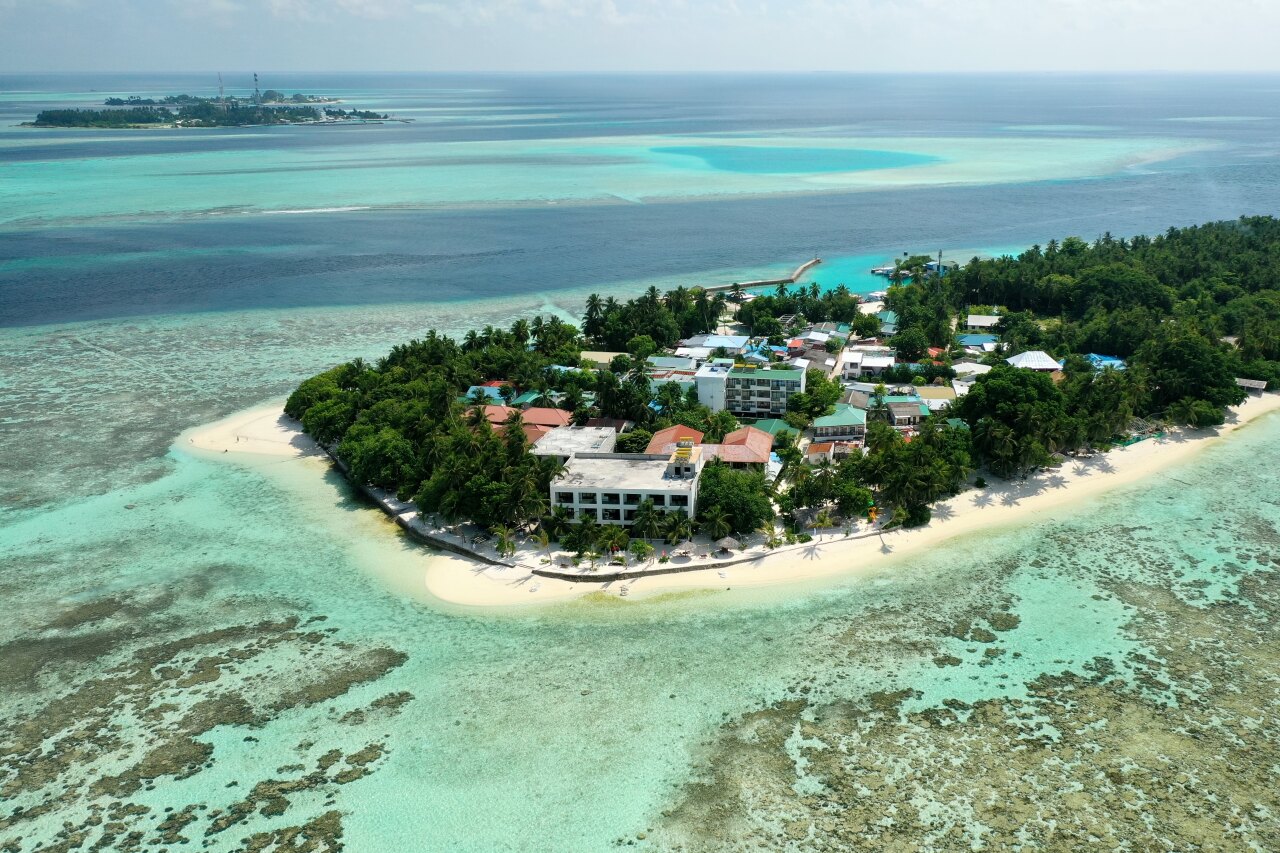 Splendida ripresa aerea con drone dell'isola locale Thinadhoo nell'atollo di Vaavu, circondata da reef e mare tropicale.