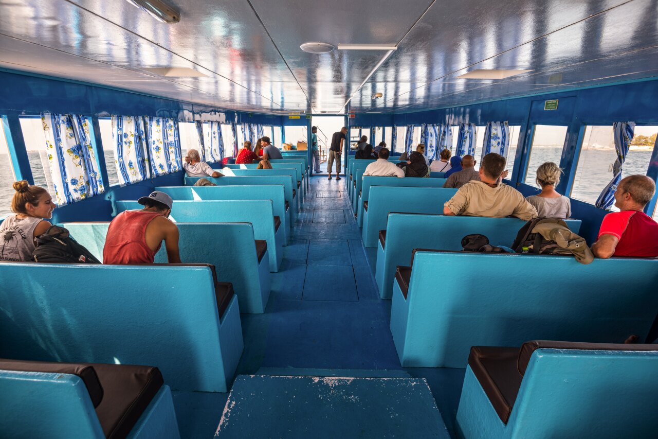 Passengers sitting inside a bright blue local ferry boat while traveling between islands in the Maldives.