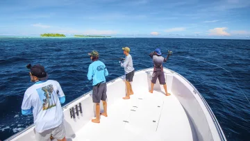 activity, people, sea - A group of men enjoying a deep sea boat fishing excursion on the clear blue ocean under a sunny sky in the tropics