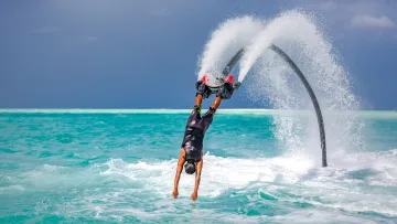 activity - A man performing an upside down dive into the turquoise sea during an exciting flyboard water sport experience