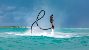 activity - A person performing a flyboard trick over the turquoise ocean waters during a sunny day in the Maldives islands.