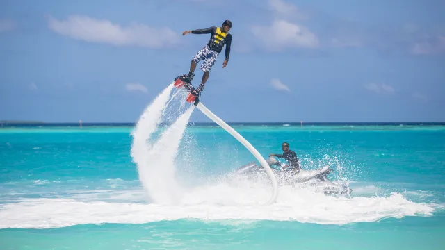 activity, sea - A person performing impressive flyboard stunts above the crystal clear turquoise tropical ocean waters in Maldives.