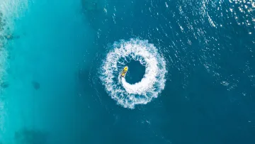activity, drone-shot - Aerial drone view of a yellow jet ski performing a perfect circular maneuver on the turquoise tropical ocean water