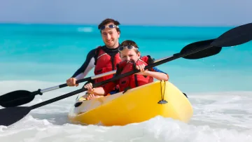 activity, people, sea - Un padre e un figlio felici pagano su un kayak giallo in acqua turchese, indossano giubbotti salvagente e occhiali.