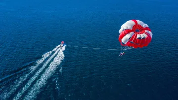 activity, people, sea, sky - A drone shot capturing a couple enjoying a thrilling parasailing adventure over the deep blue ocean in Maldives.