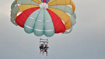 activity, sky - A couple soaring through the sky while parasailing, pulled by a boat above the clear waters of the Indian Ocean.