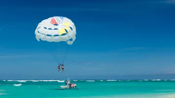activity, sea - A couple enjoying a thrilling parasailing flight pulled by a motorboat over the turquoise Maldivian ocean waters