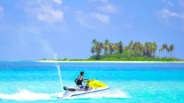 activity, sea - A young man riding a yellow jet ski across the crystal clear turquoise water of the Maldives near a tropical island.