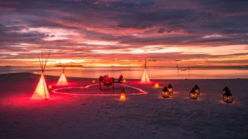 activity, luxury, sunset - Un tavolo da cena romantico e privato su una spiaggia di sabbia bianca al tramonto, decorato con teepee e lanterne.