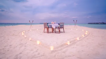 activity, sunset - Un tavolo da cena privato e romantico allestito su una spiaggia di sabbia bianca, circondato da un cuore di candele al crepuscolo