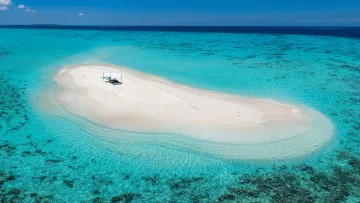 activity, beach, drone-shot, sea - Aerial view of a secluded white sandbank surrounded by vibrant turquoise water with a sun canopy for relaxation.