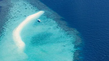 activity, drone-shot, sea - An aerial drone perspective of a pristine white sandbank surrounded by shallow turquoise lagoons and a speed boat.