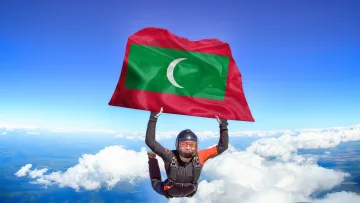 activity, sky - Un paracadutista professionista in caduta libera che tiene la bandiera delle Maldive contro un cielo azzurro.
