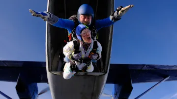 activity, sky - Una donna e il suo istruttore di paracadutismo tandem si lanciano da un aereo nel cielo blu sopra le isole.