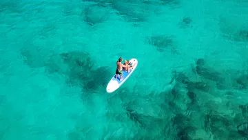 activity, drone-shot, sea - Vista aerea di una coppia in piedi su una tavola da stand up paddle nelle acque turchesi di una laguna tropicale.