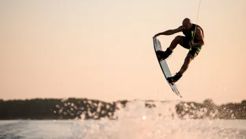 activity, sea, sunset - Atleta professionista che esegue un impressionante salto in alto con il wakeboard sopra il mare al tramonto.