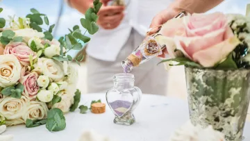 activity - A close-up of a couple performing a romantic sand unity ceremony during their island wedding in the Maldives.