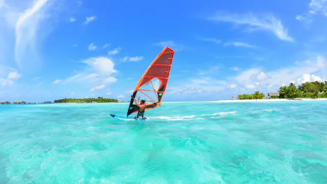activity, sea - Un windsurfista scivola sulle limpide acque turchesi della laguna sotto un cielo blu brillante in una giornata di sole.