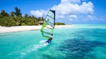 activity, nature, sea - Un windsurfer scivola sulle acque turchesi di una laguna tropicale con la vegetazione dell'isola sullo sfondo.