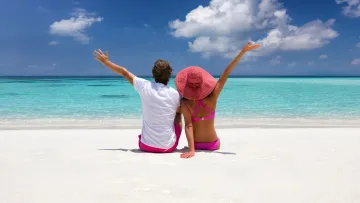 beach, people, relax, sea - A couple sitting on a tropical beach with white sand and a vast blue sky.