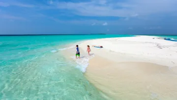 beach, people, relax, sea - Children playing in shallow turquoise water and a woman relaxing on a remote white sandbank under a clear blue sky