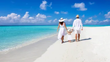 beach, people - A young family dressed in white walks hand in hand along a pristine white sandbank with turquoise water and blue sky.