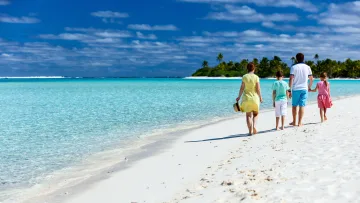 beach, people - Una famiglia di quattro persone cammina lungo la riva di sabbia bianca di una laguna turchese con palme verdi sullo sfondo