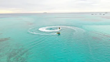 activity, sea - Vista aerea di una moto d'acqua che traina un gruppo di turisti su un tubo gonfiabile nella limpida laguna tropicale