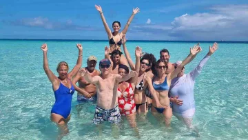 people, sea - A cheerful group of friends and family posing with arms raised in the clear turquoise shallow water of a lagoon.