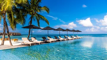 luxury, relax, resort, sea - Fila di lettini con ombrelloni neri accanto a una piscina a sfioro cristallina che si affaccia sull oceano.