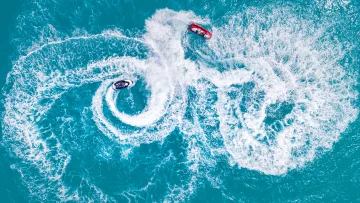 activity, drone-shot, sea - Aerial top down view of two jet skis performing high speed circular maneuvers on the bright turquoise tropical sea