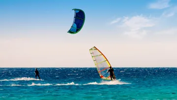 activity, sea - Kitesurfer e windsurfer cavalcano le onde blu dell'oceano tropicale sotto un cielo limpido in una giornata ventosa.