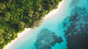 Stunning aerial drone shot of the tropical white sand beach and coral reef surrounding Dhigurah local island.