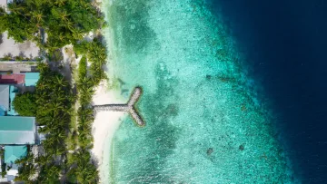 drone-shot, local-island, nature, sea - Aerial drone shot of Felidhoo local island in Vaavu Atoll showing the tropical coast and a stone breakwater jetty.