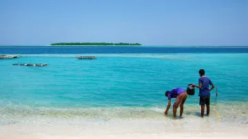 local-island, people - Two local men fishing in the crystal clear turquoise lagoon of Felidhoo Island in the Vaavu Atoll, Maldive Islands.
