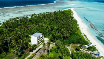 drone-shot, local-island, nature - Aerial view of lush green Fenfushi Island in Alifu Dhaalu Atoll with a white building, white sand beach and crystal lagoon.