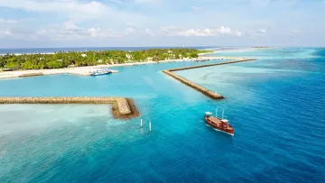 drone-shot, local-island, sea - Aerial drone shot of a traditional wooden dhoni boat approaching the harbor of Fenfushi island in Alifu Dhaalu atoll