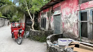 culture, local-island - Red cargo tricycle parked on a sandy street next to a weathered red building on Fenfushi Island, Alifu Dhaalu Atoll