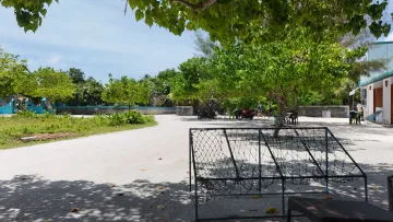 local-island - View of a sandy street on the local island of Fulhadhoo in the Baa Atoll, shaded by large lush green tropical trees.