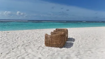 beach, bikini-beach, local-island, relax - Wicker lounge chairs on the white sand of Fulhadhoo beach with a view of the turquoise sea in Baa Atoll, Maldives.