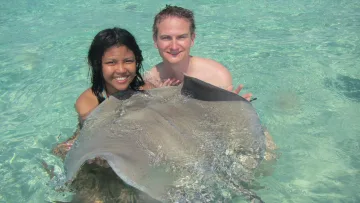 animal, local-island, people - A couple snorkeling and interacting with a friendly stingray in the crystal clear water of Fulidhoo, Vaavu Atoll.