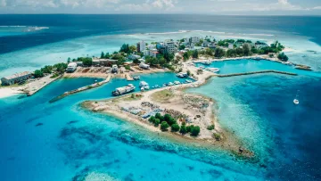 drone-shot, local-island, sea - Aerial perspective of the harbor and buildings on Gulhi Island, Kaafu Atoll, surrounded by crystal clear lagoon waters.