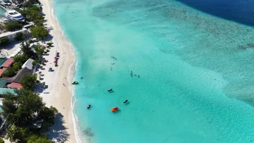 beach, bikini-beach, drone-shot, local-island, sea - Aerial shot of the crystal clear turquoise water at Gulhi local island in Kaafu Atoll with people swimming and boats.
