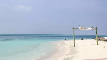 beach, local-island, sea - Traditional wooden boat sign on Gulhi island beach in Kaafu Atoll, with turquoise lagoon water and white sandy shore.