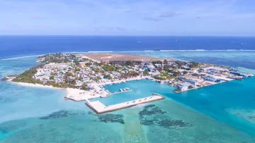 drone-shot, local-island - Aerial drone shot capturing the local island of Hinmafushi in the Kaafu Atoll, featuring the harbor and blue waters.