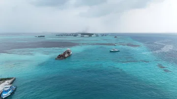 drone-shot, sea - Aerial view of a shipwreck in the turquoise lagoon near the local island of Hinmafushi, Kaafu Atoll, Maldives.
