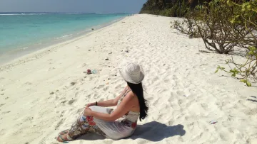 beach, local-island, people, relax - Woman in hat sitting on the white sand of Hulhumalé local island, Kaafu Atoll, enjoying the turquoise ocean view.